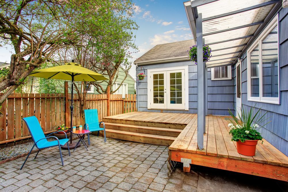 Backyard Patio With Wooden Deck, Blue Chairs, Yellow Umbrella — Property Transfer Professionals In Warnervale, NSW