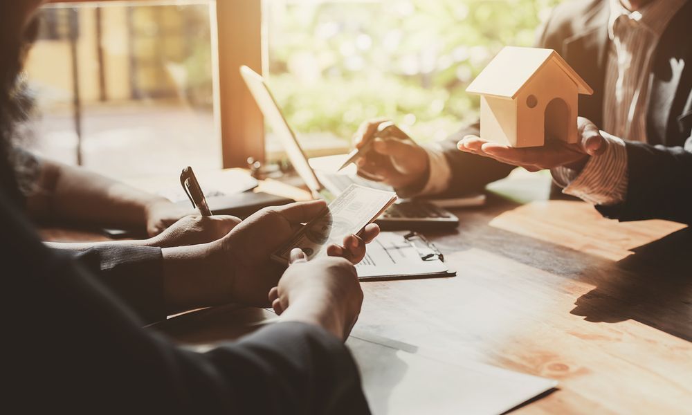 People at a Table, Discussing Paperwork and a Small House Model — Property Transfer Professionals In Woy Woy, NSW