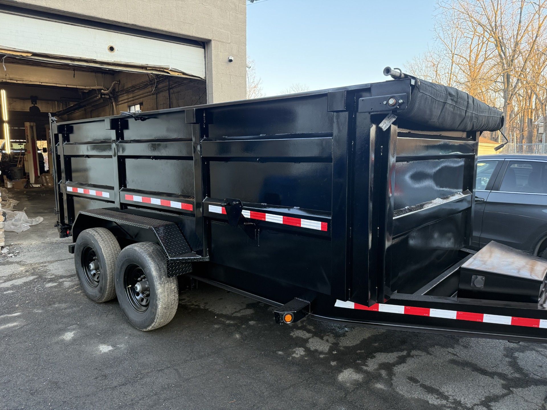 Restored dump trailer with black bedliner coating and tarp system after professional refurbishment