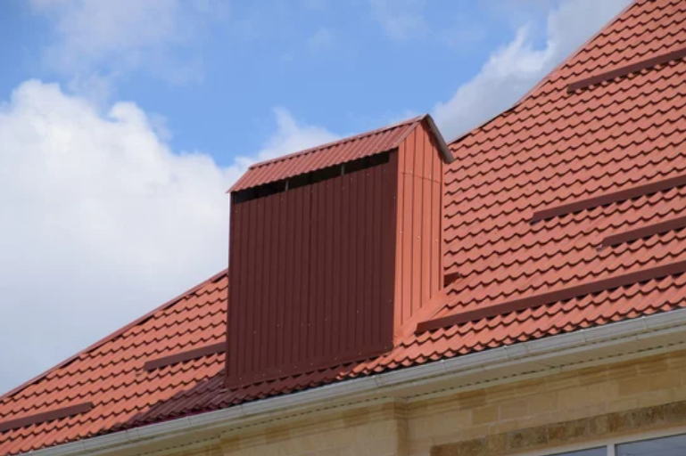 Close-up of red metal roofing sheets overlapping each other, creating a vibrant and durable covering for a building.