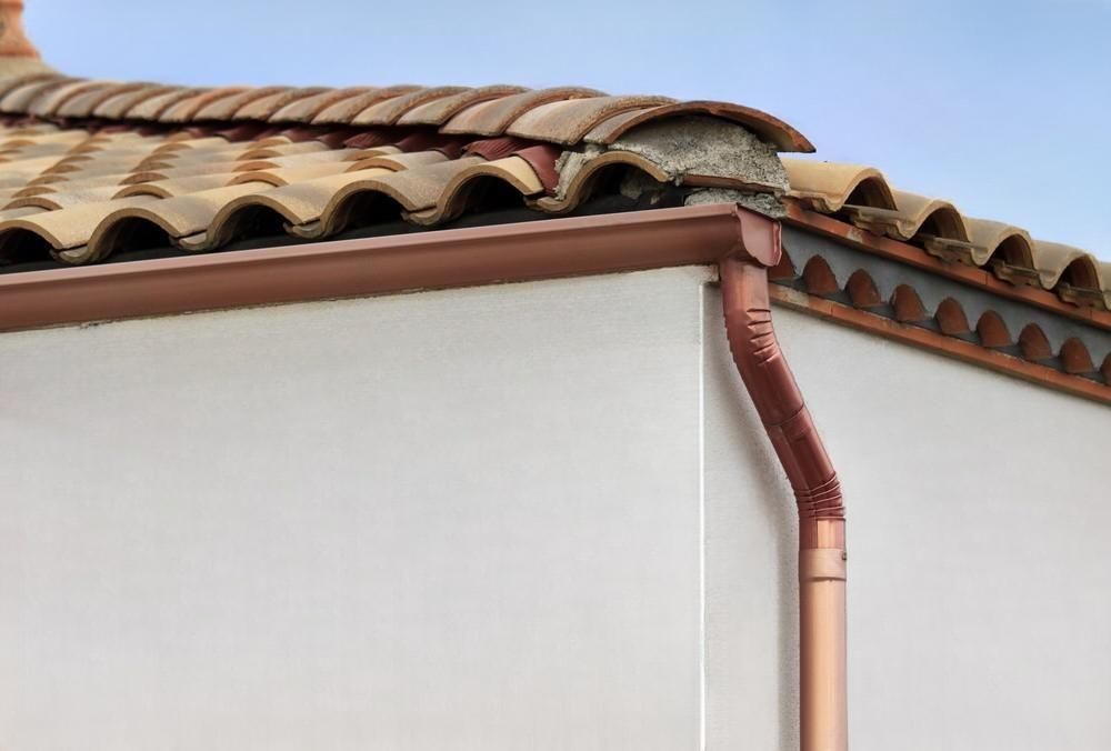 A copper gutter is attached to the side of a building