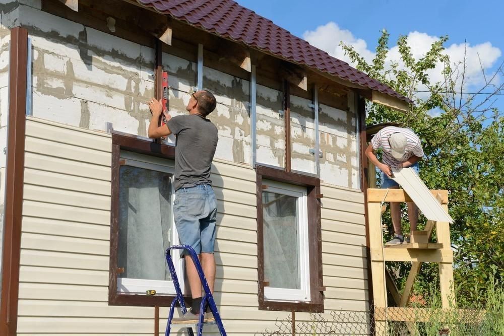 Two workers diligently polishing a vinyl-sided apartment building.