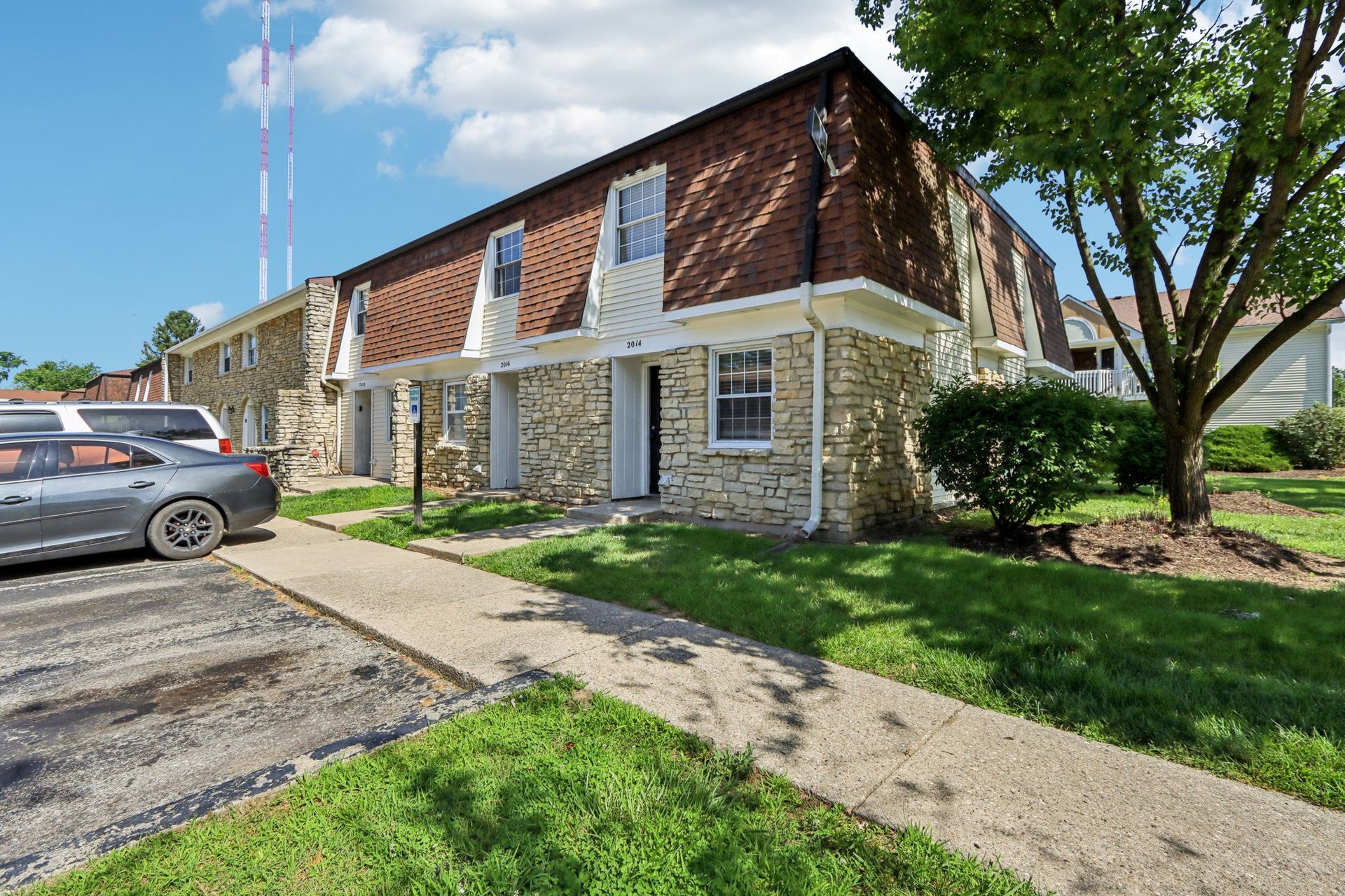 Townhouse complex with stone facade and red brick roof on a sunny day.