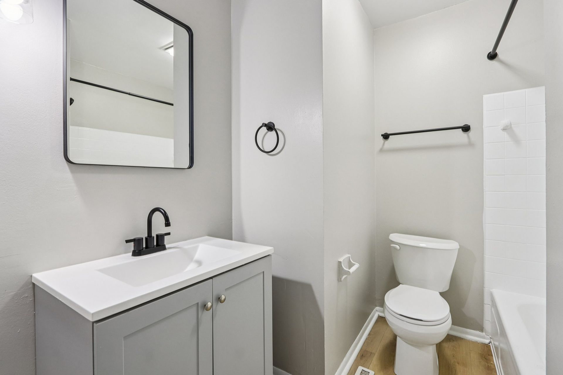 Bathroom with gray vanity, white countertop, black fixtures, and toilet.