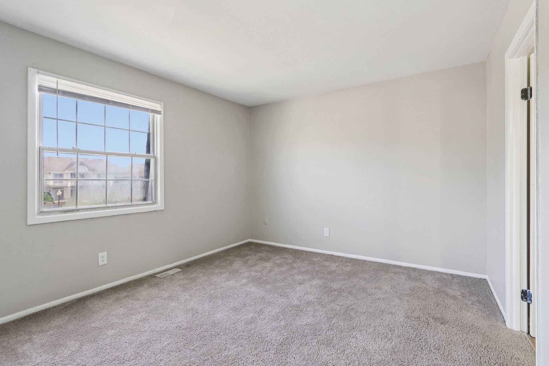 Empty bedroom with a window, gray walls and carpet.