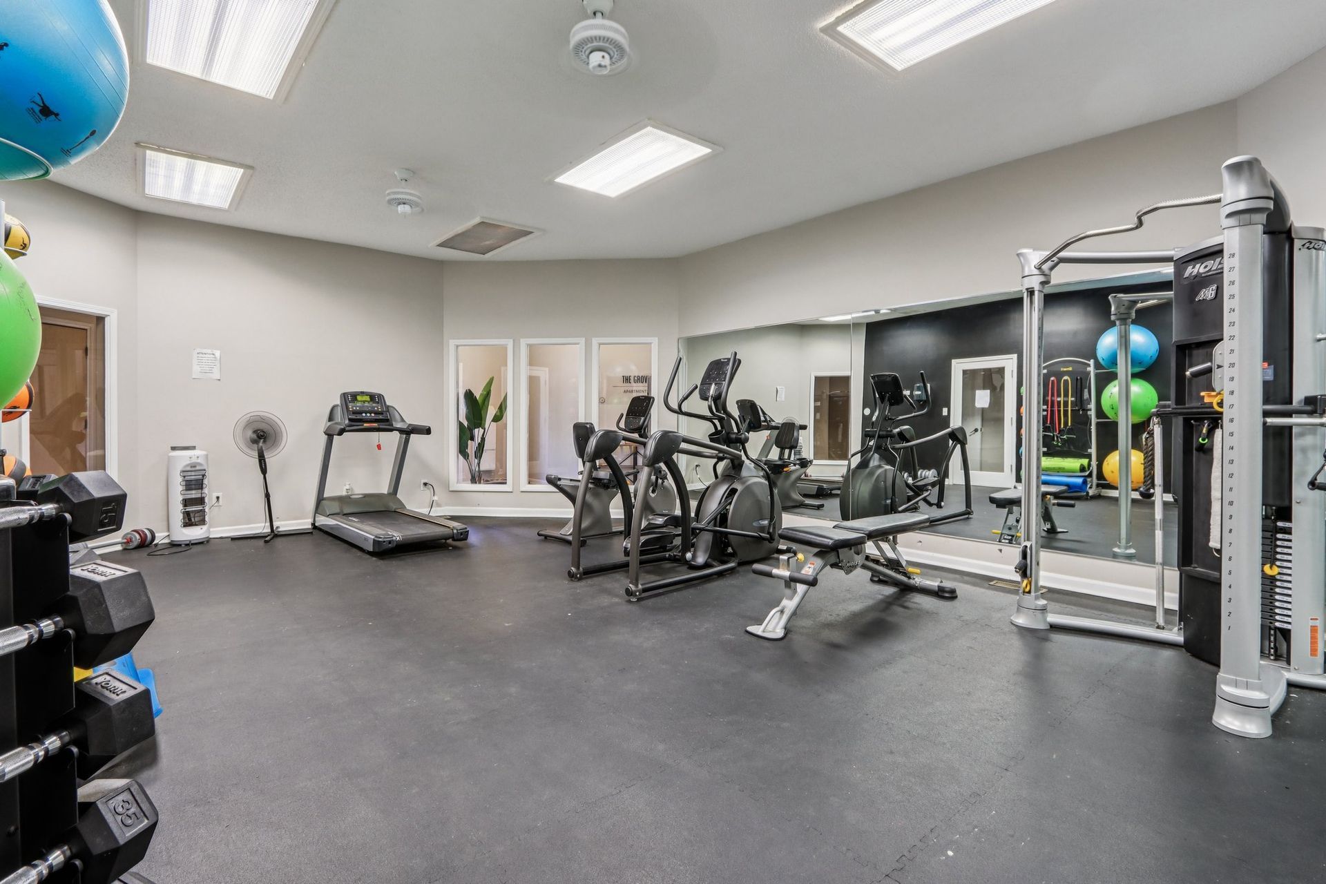 Gym with exercise equipment, including treadmill, weights, and weight machine.