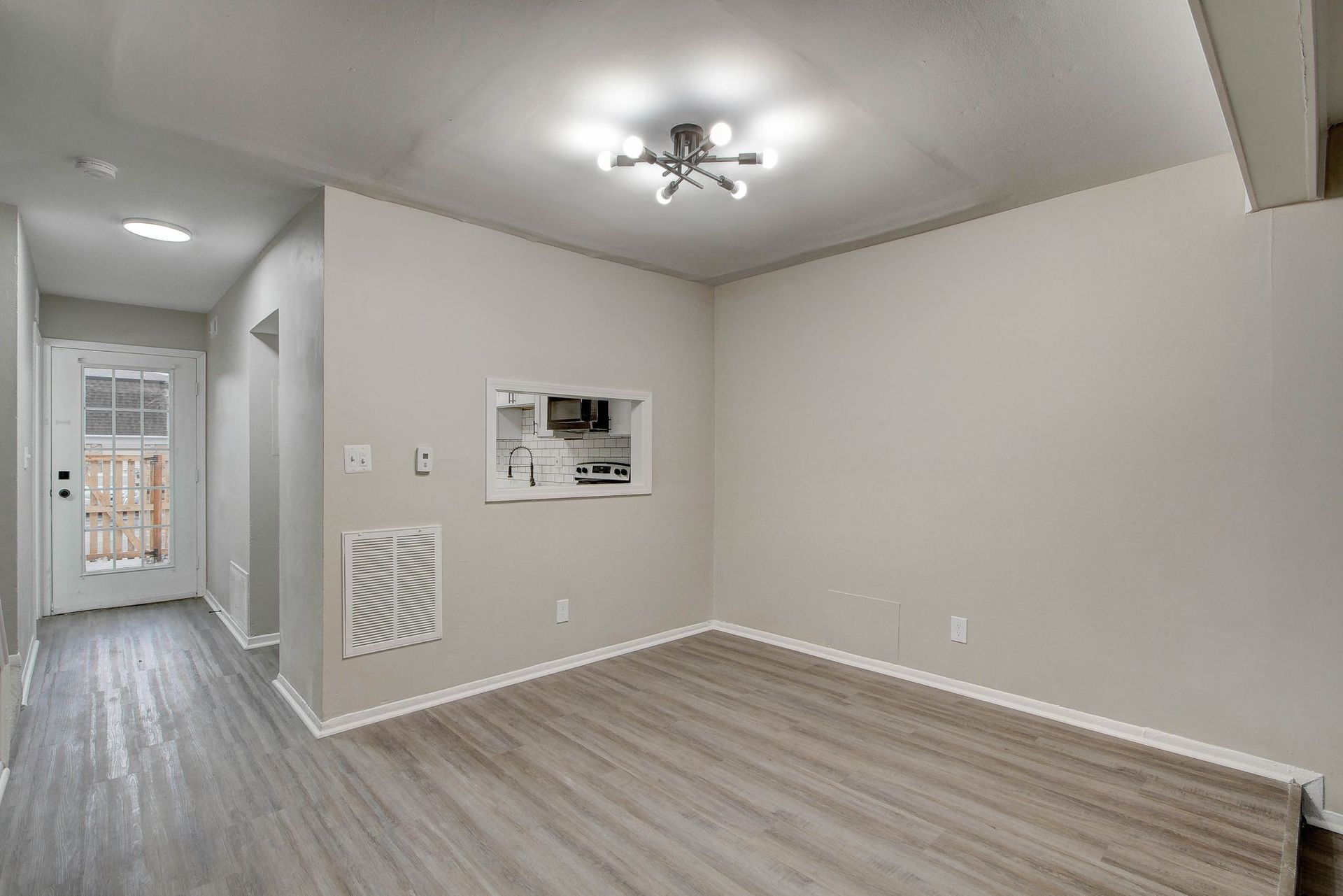 Empty dining room with gray flooring and walls, doorway and light fixture.