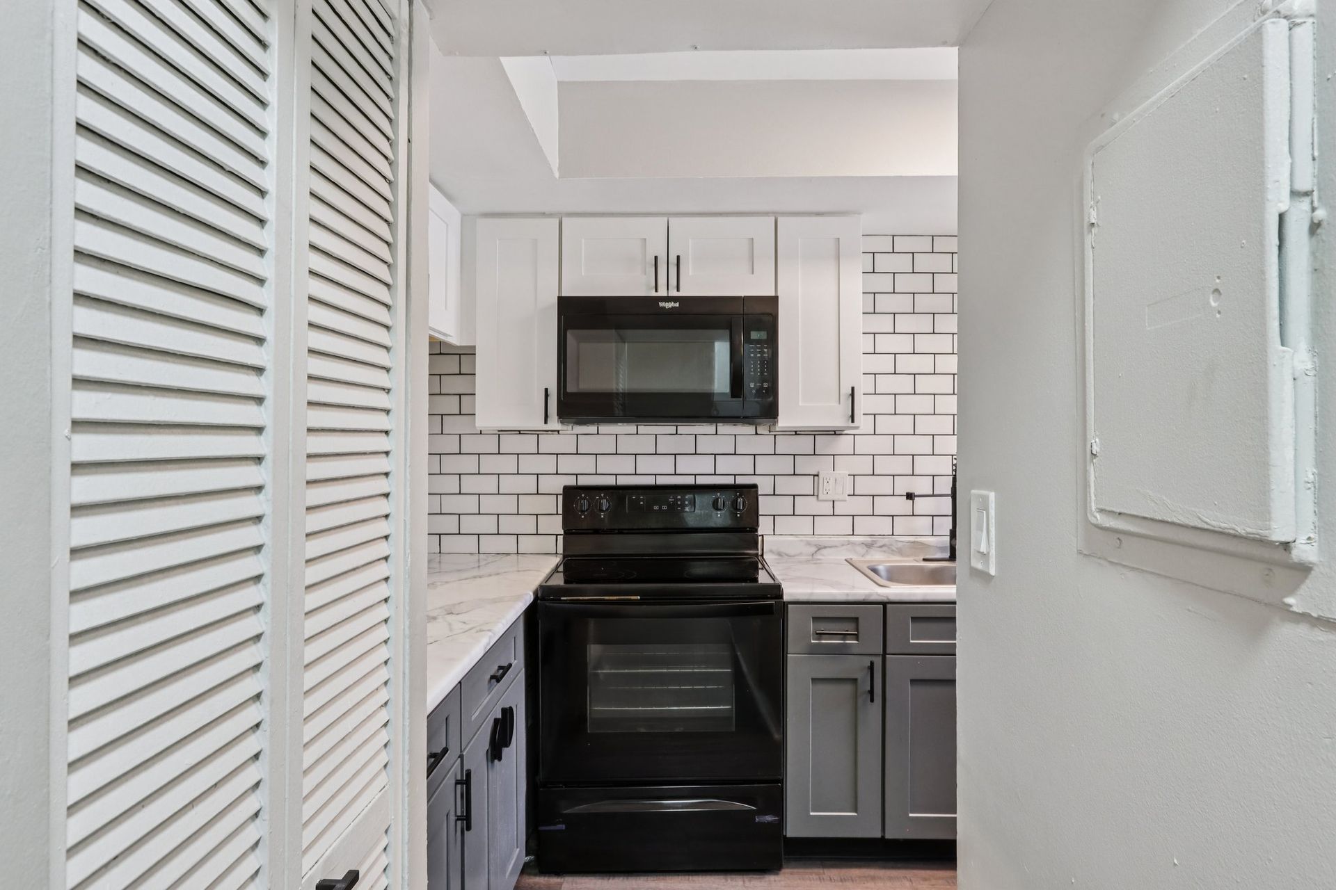Kitchen with white cabinets, subway tile backsplash, and black appliances.