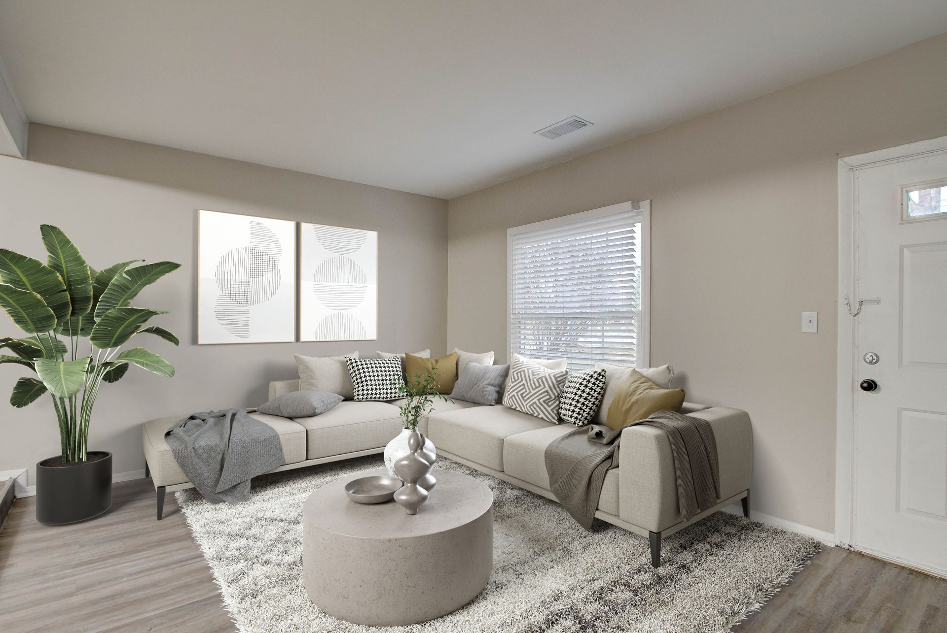 Beige living room with sectional sofa, coffee table, and plant; two artworks on wall.