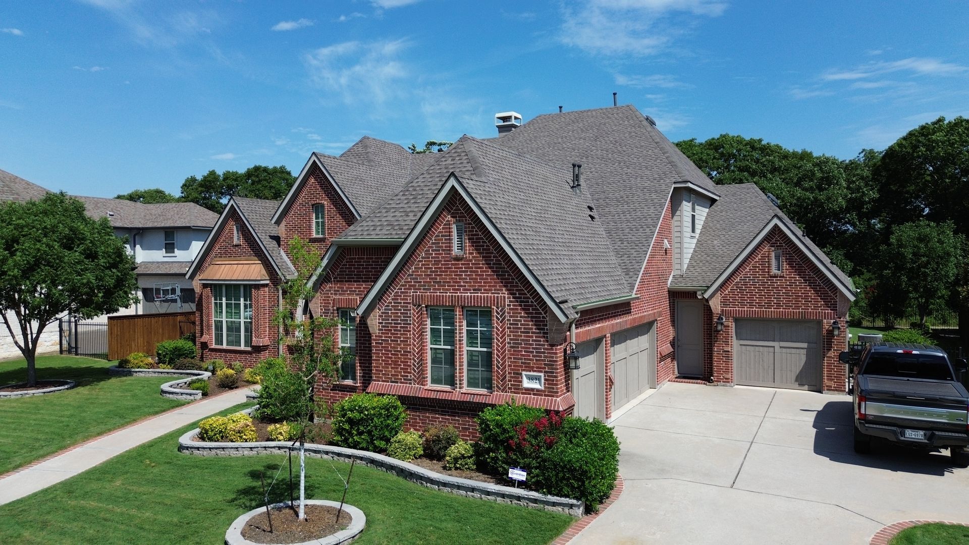 Brick house with a two-car garage and landscaping under a blue sky.