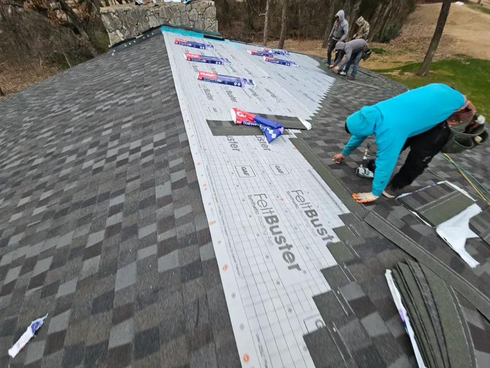 Roofers installing shingles on a roof, using a blue and gray color scheme on a sunny day.