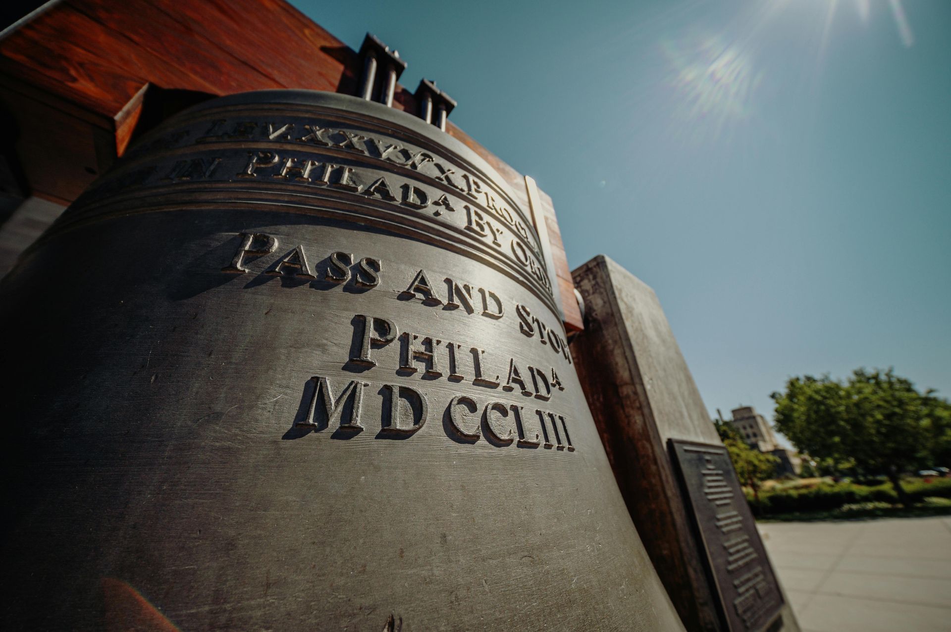 Close-up of a large engraved stone monument beside a red-brick building under a bright blue sky.