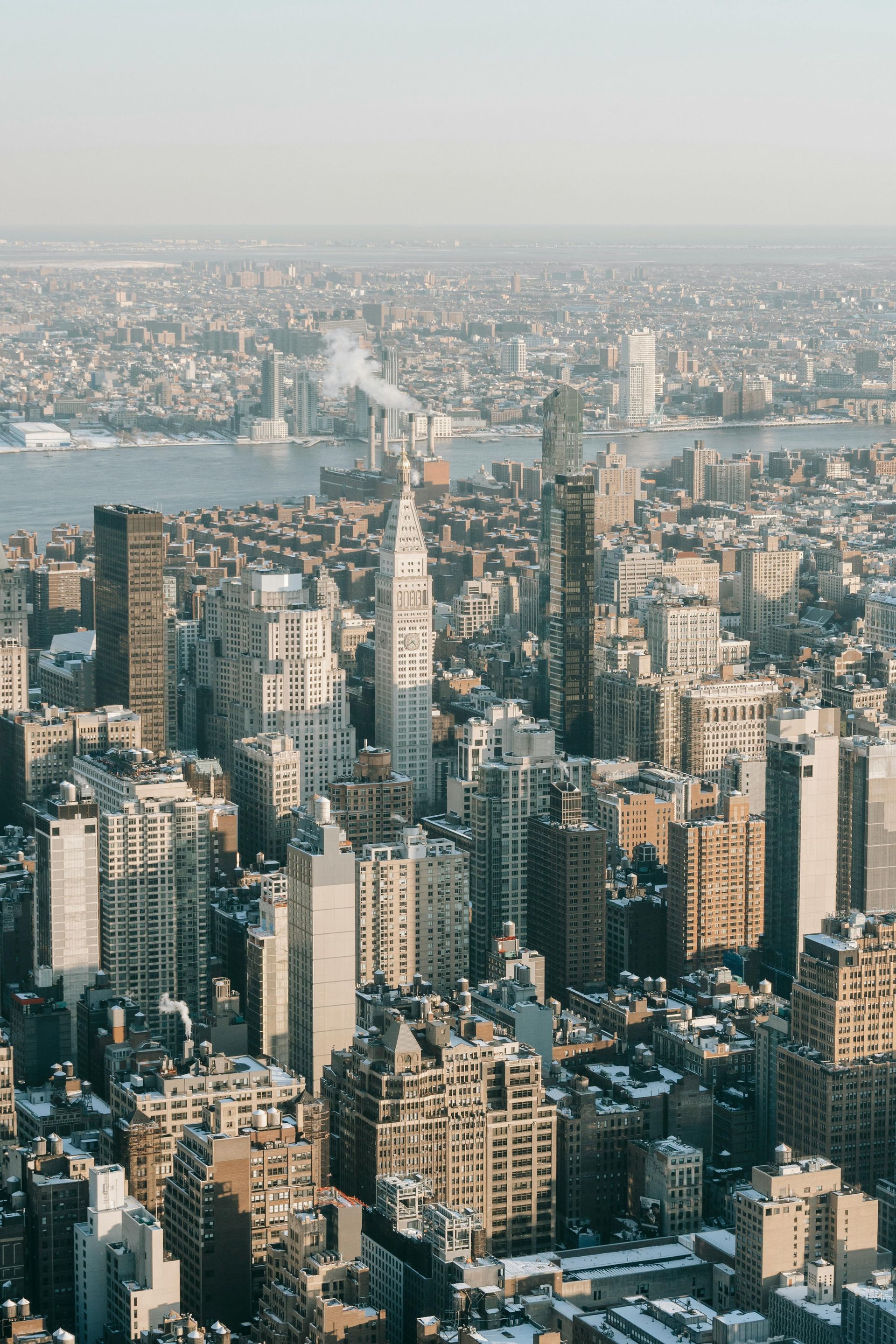 Aerial view of a dense city skyline with high-rise buildings and a river in the distance