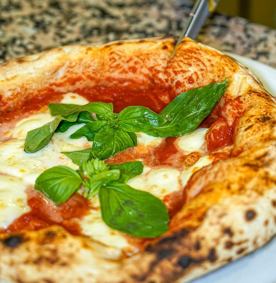 Pizza quadrata condita con salsa di pomodoro, mozzarella e basilico.