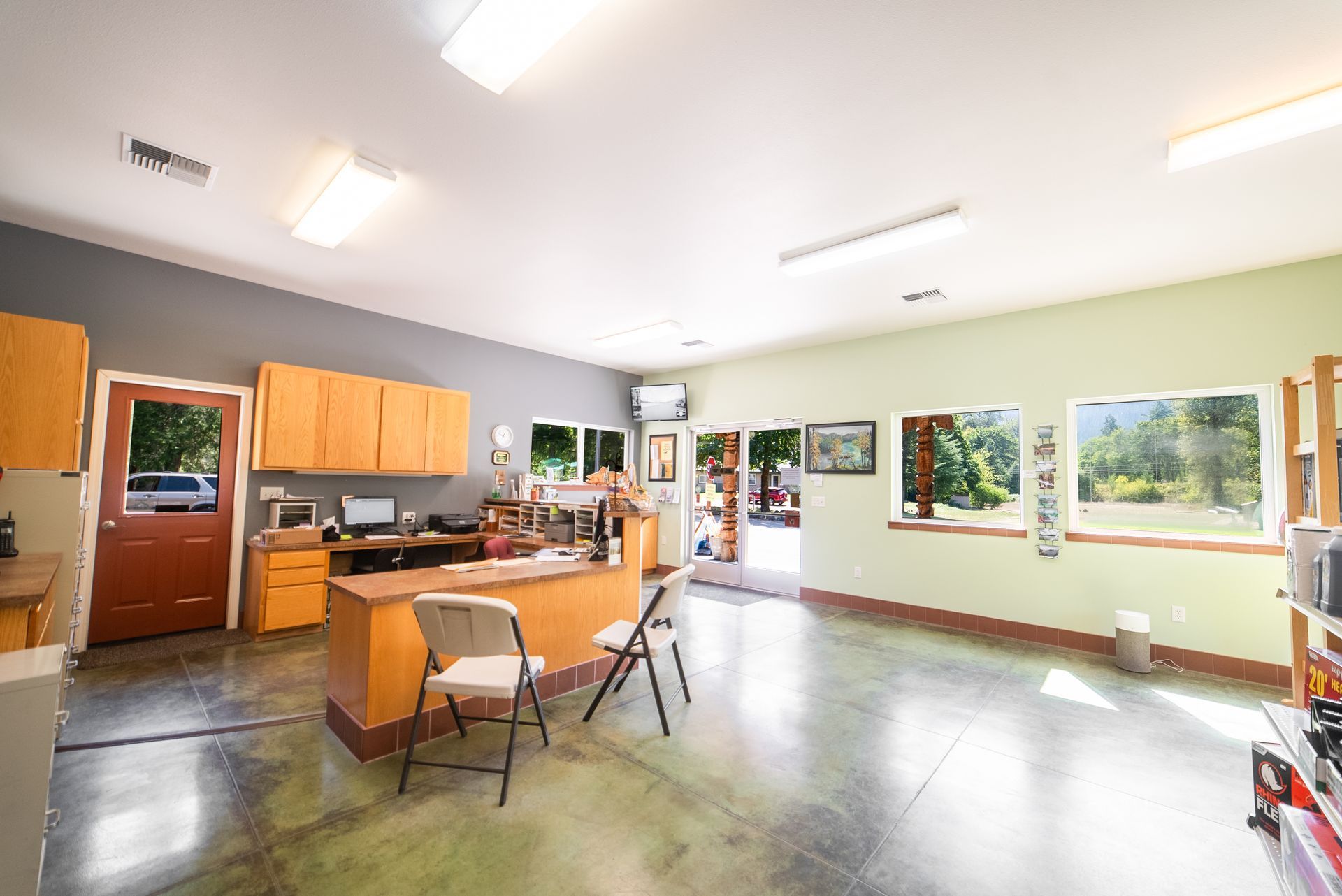 Interior of a garage converted into an office, with cabinets, desk, windows, and an open doorway.