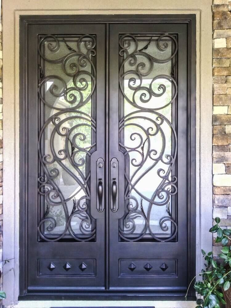 A close up of a wrought iron door on a brick wall.