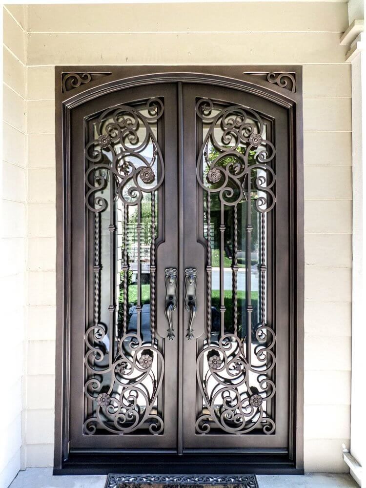 A pair of wrought iron doors on a porch of a house.