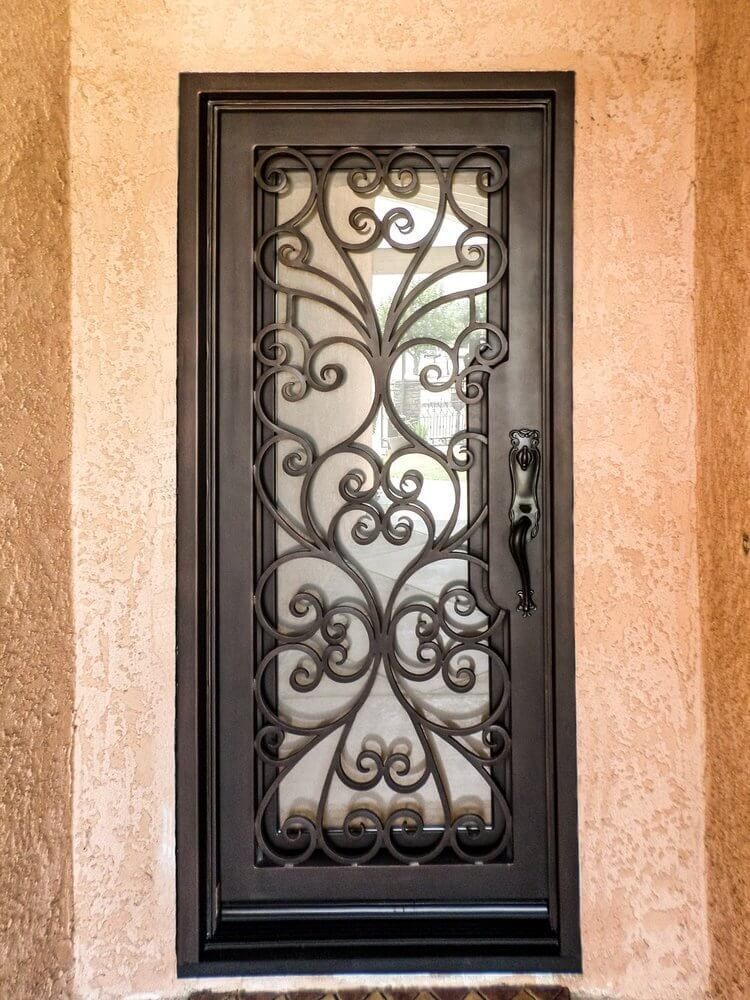 A wrought iron door with a glass window is on a wall.
