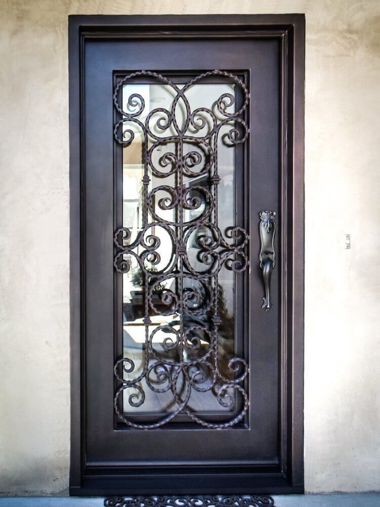 A wrought iron door with a glass window is on a wall.