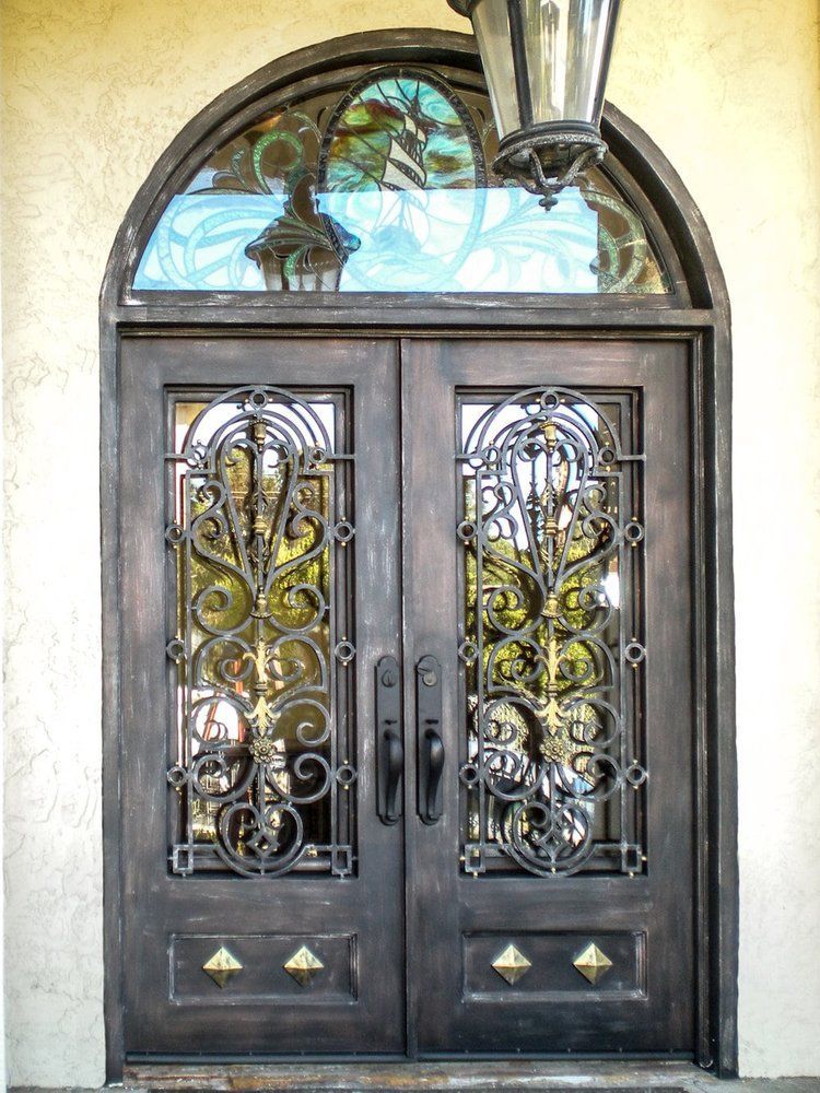 A wrought iron door with a stained glass window and a lantern hanging from the ceiling.
