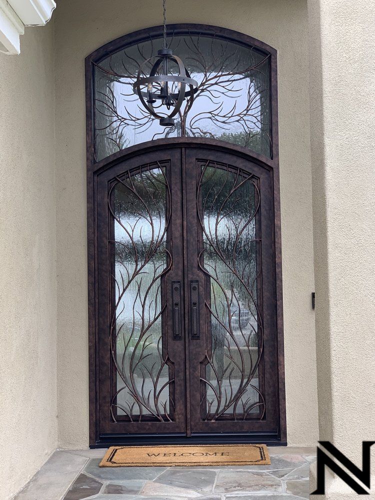 A wrought iron door with a welcome mat underneath it