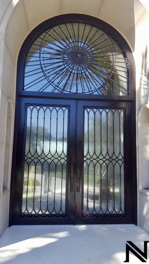 A pair of black double doors with a wrought iron design on the top of them.