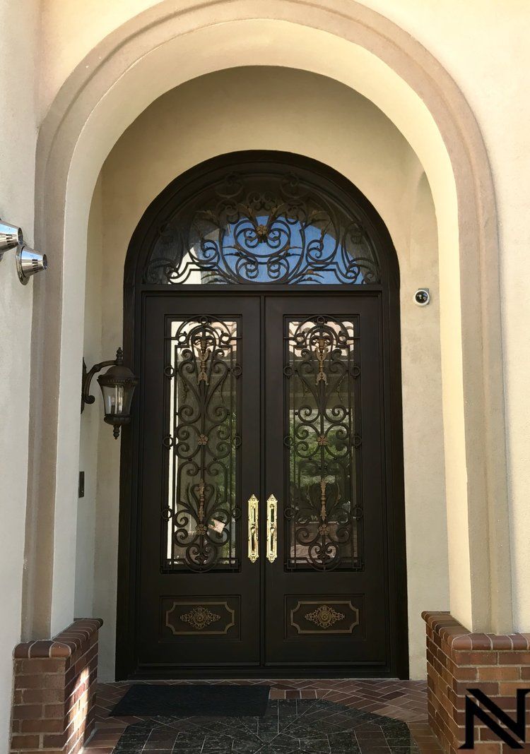 The front door of a house with a wrought iron door and arched window.