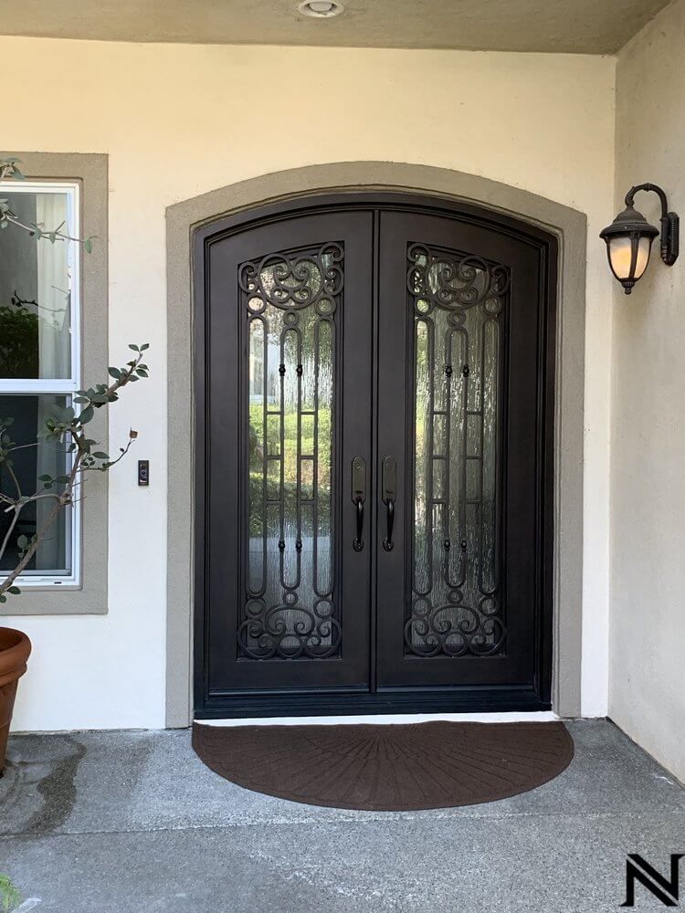 The front door of a house with a wrought iron door and a window.