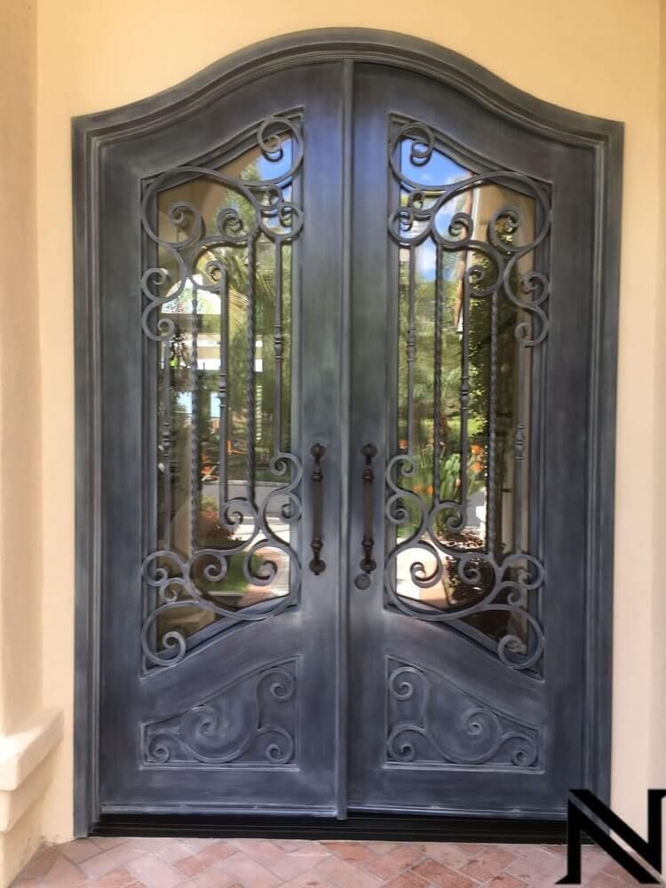 A pair of wrought iron doors are sitting on top of a tiled floor.