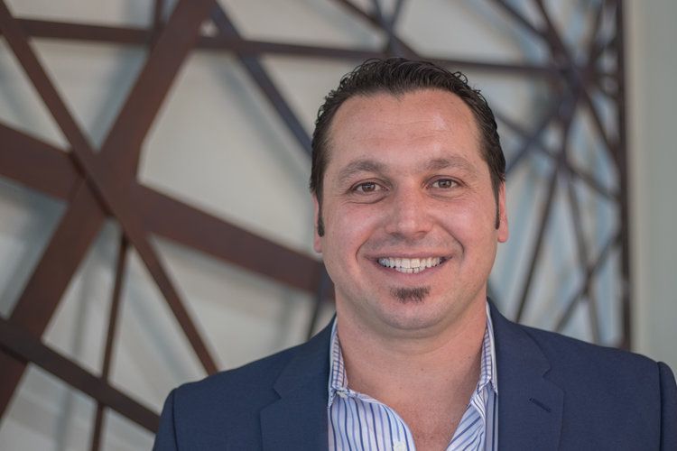 A man in a suit and striped shirt is smiling for the camera.