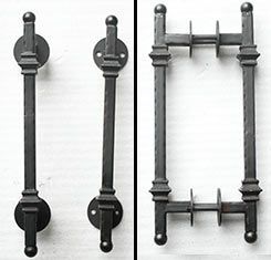 A pair of black wrought iron door handles on a white surface.