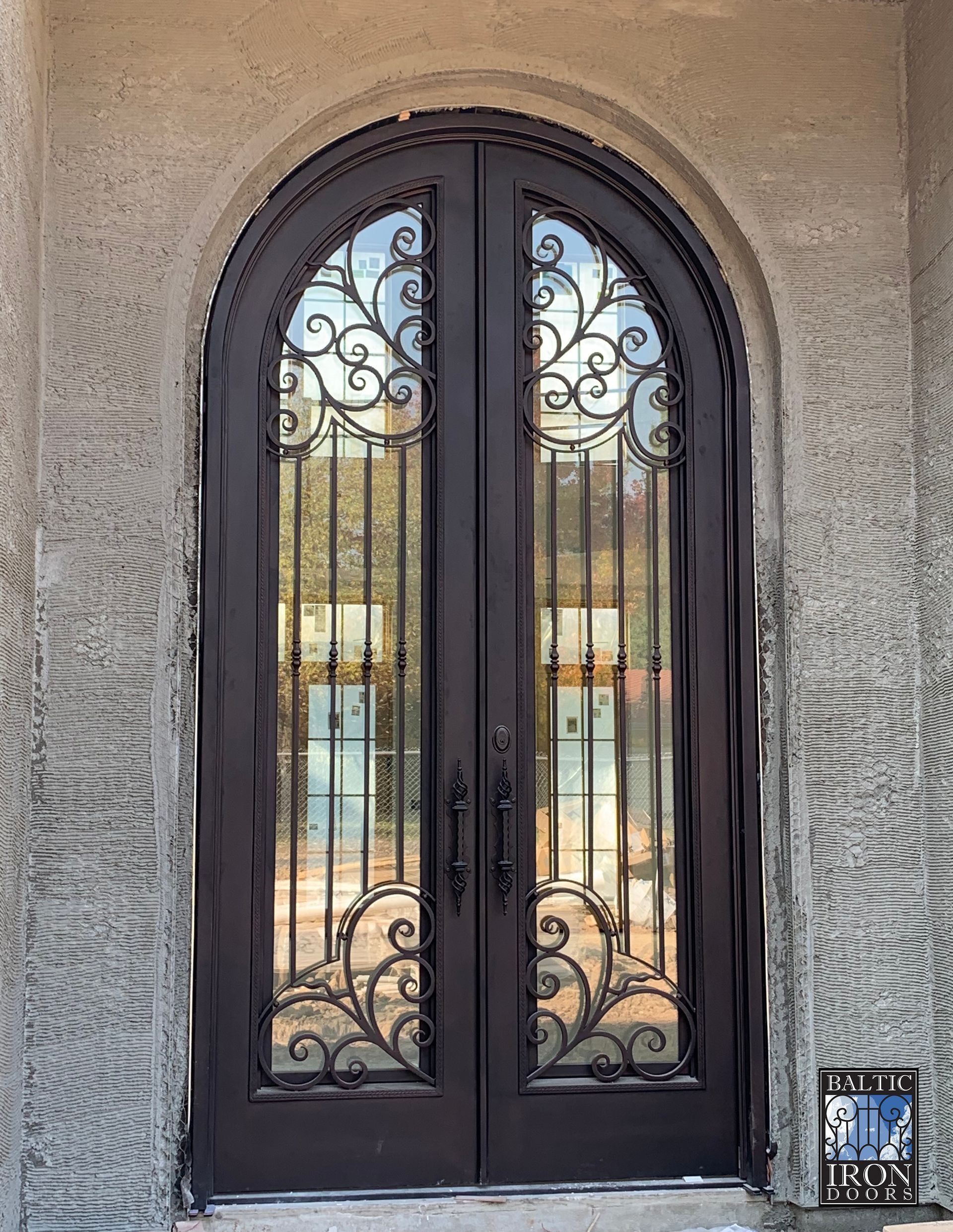 A brick wall with a wrought iron door in front of it.