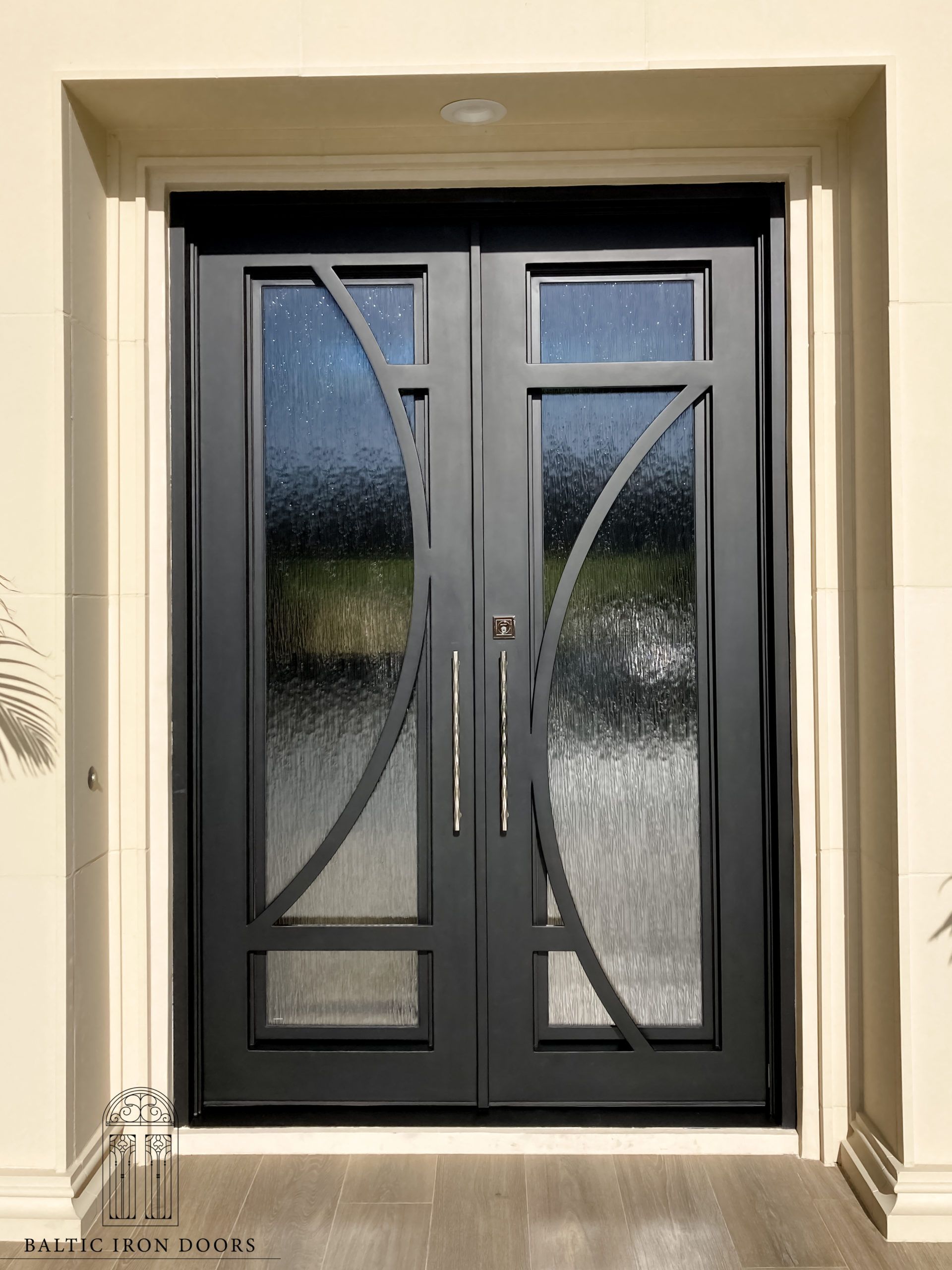 A black double door with a lot of glass is on a white wall.