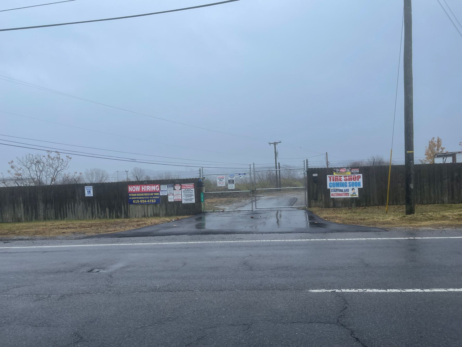 A rainy day with a lot of signs on the side of the road.