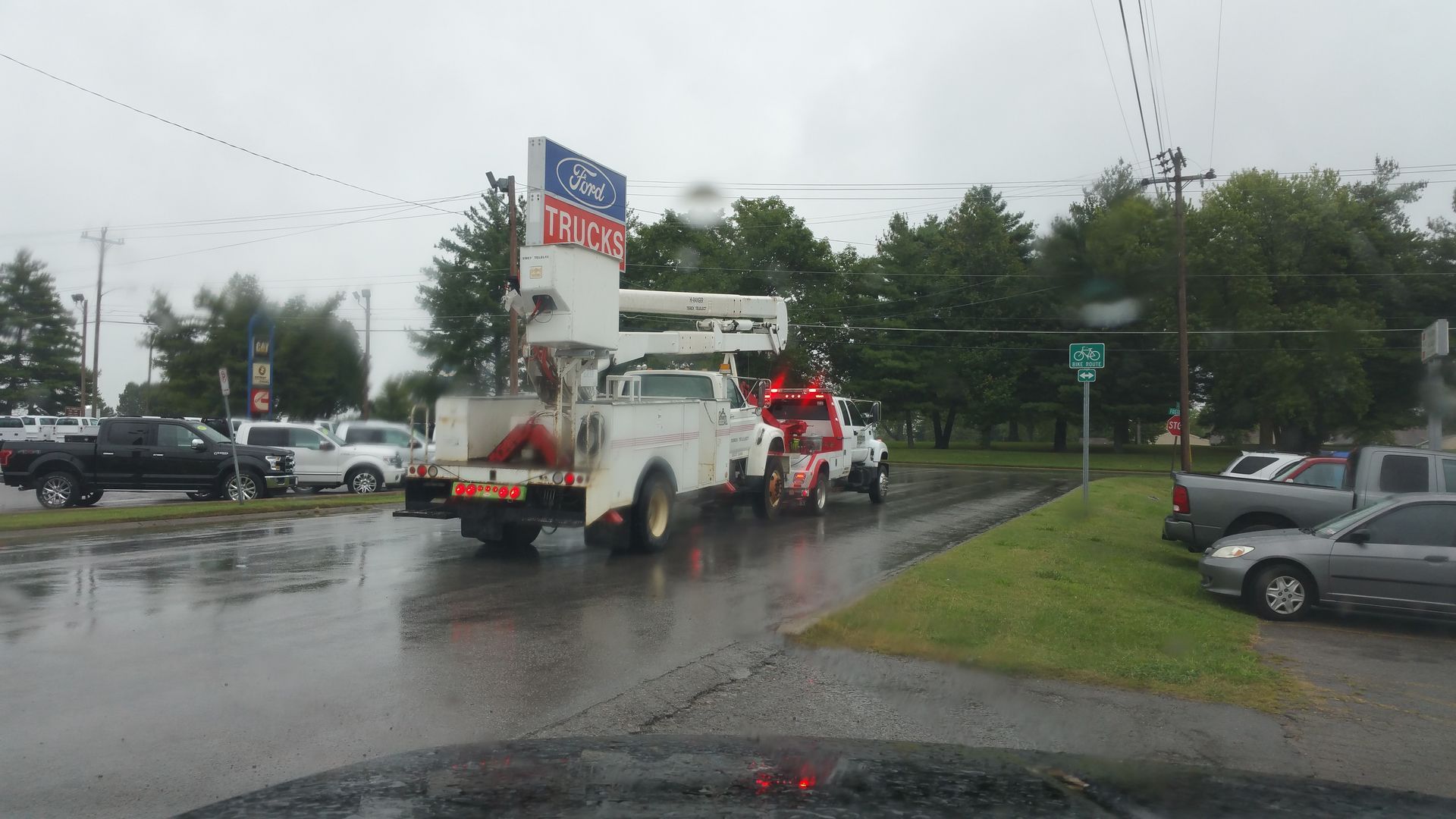 A tow truck is parked on the side of the road in the rain.