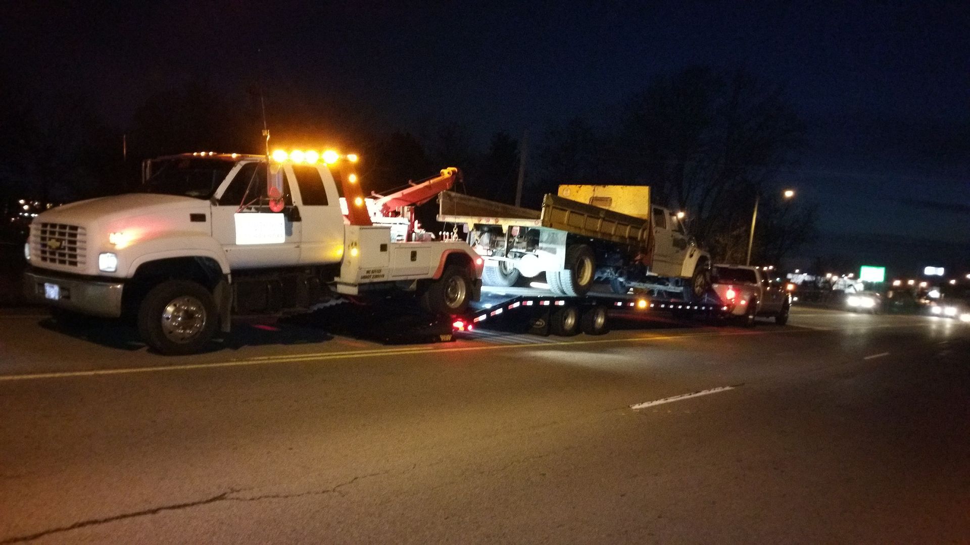 A tow truck is driving down a highway at night.
