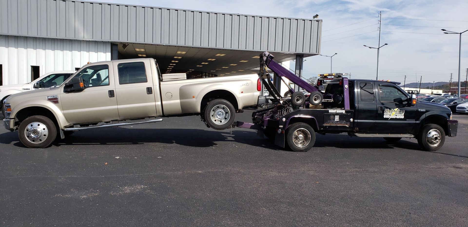 A tow truck is pulling a pickup truck in a parking lot