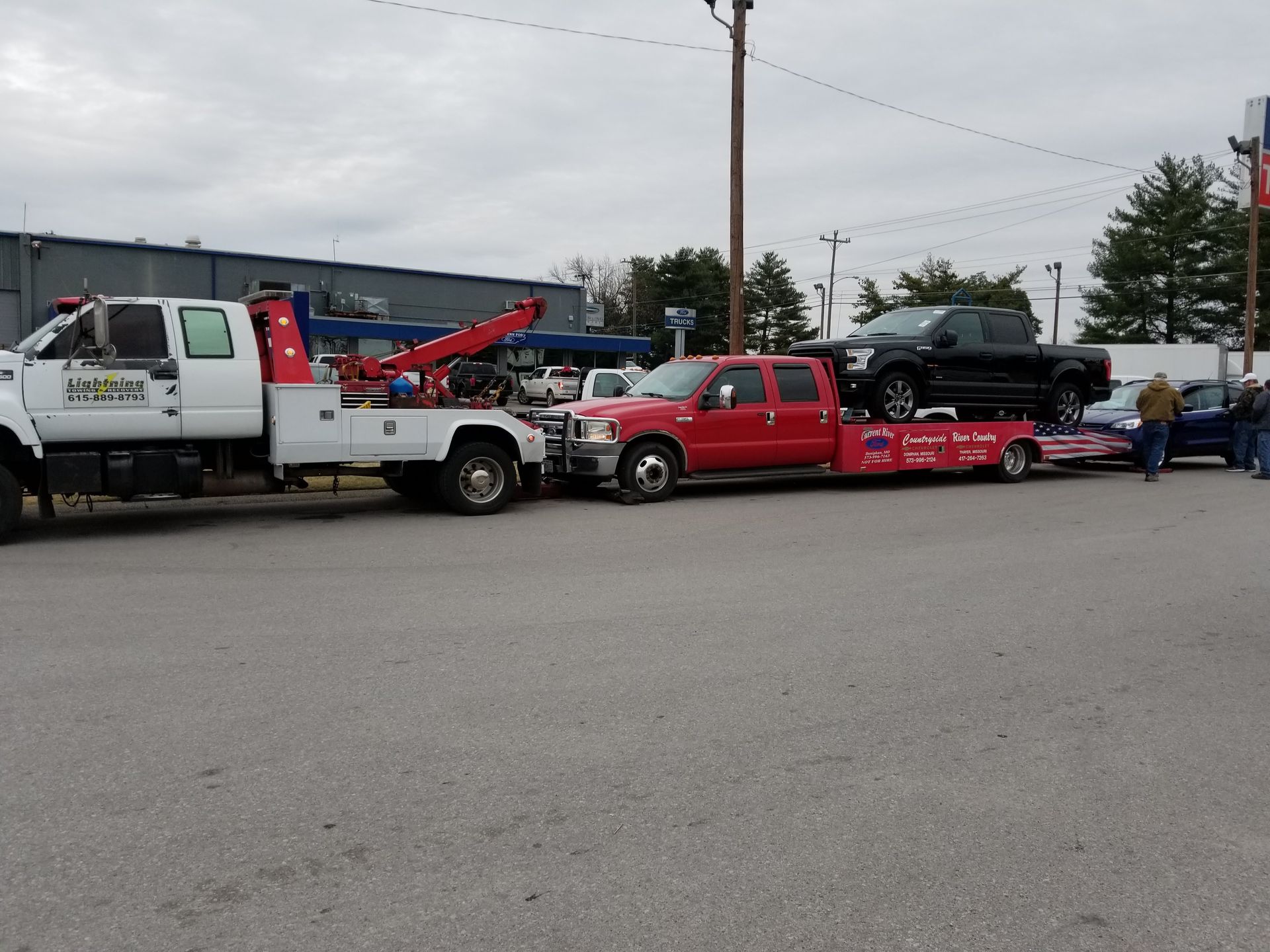 A red tow truck is carrying a black truck