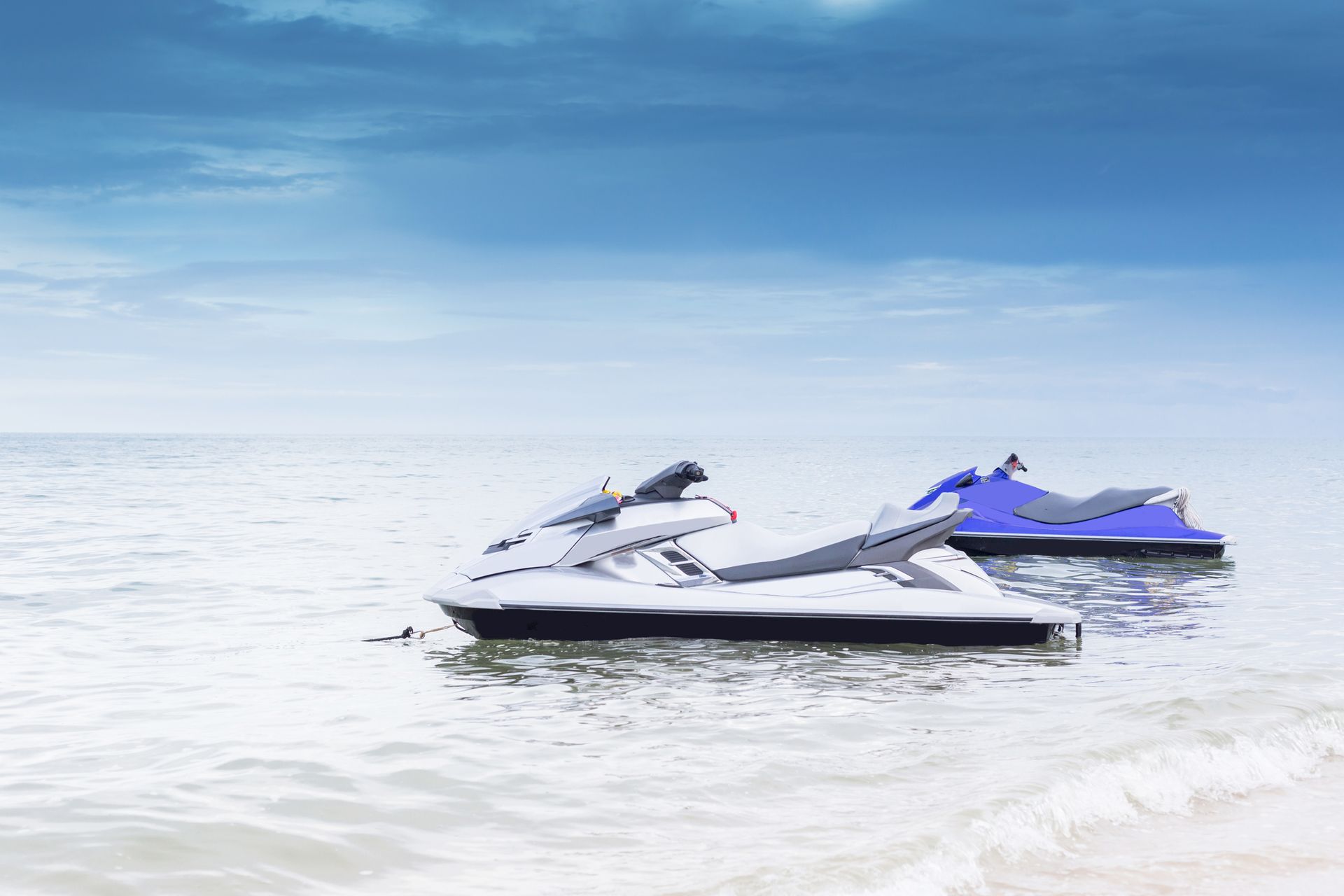 Two jet skis are floating on top of a body of water.
