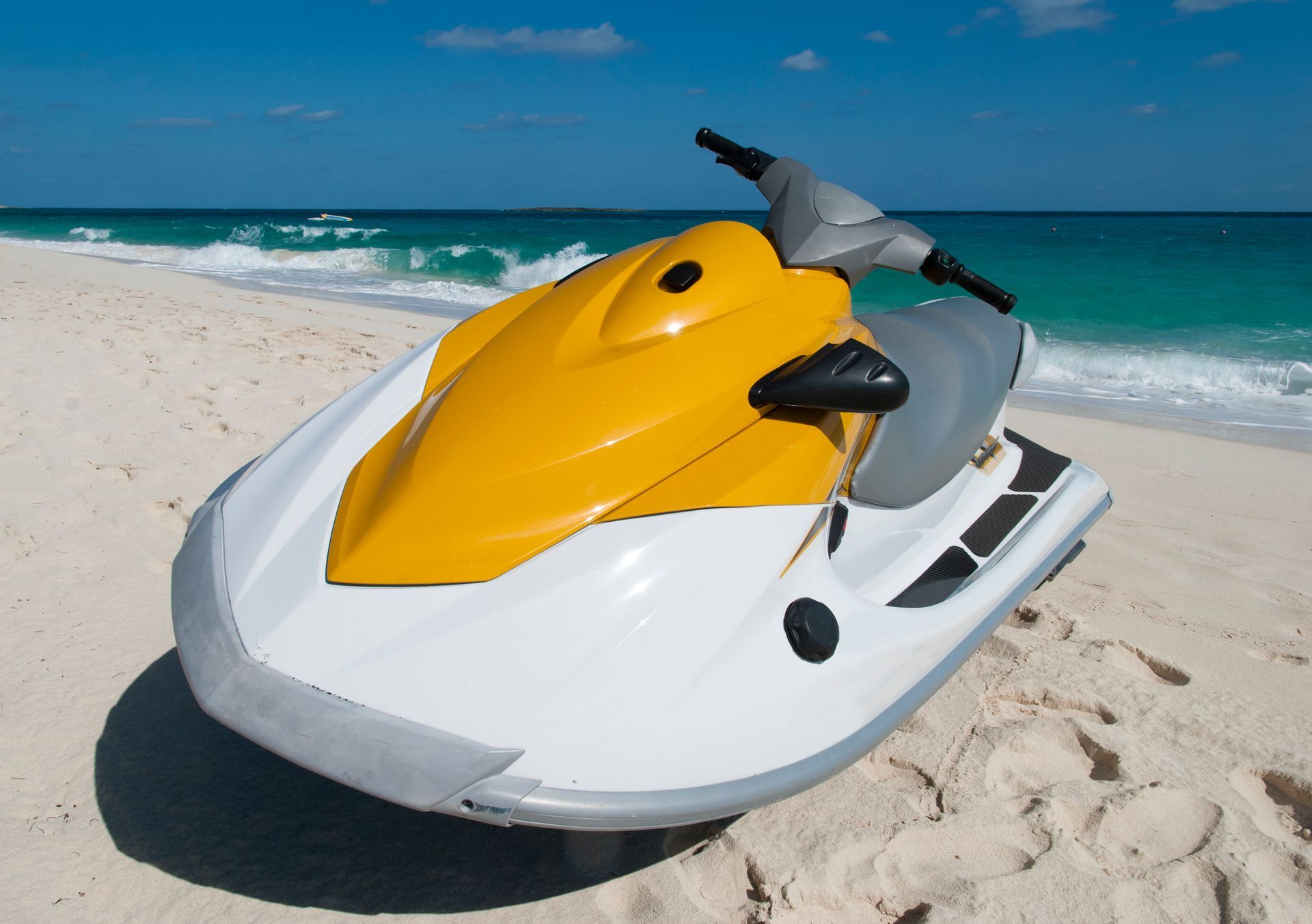 A yellow and white jet ski is parked on the beach