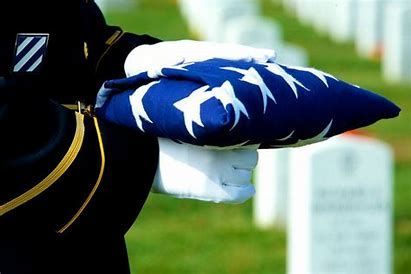 a soldier is holding an american flag in front of a cemetery .