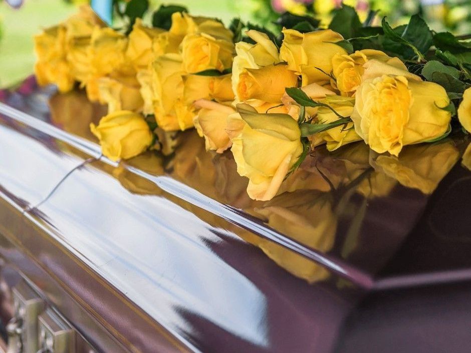 a coffin with yellow roses on top of it .