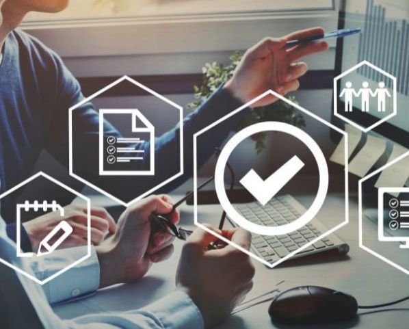 Two people are sitting at a desk looking at a computer screen.