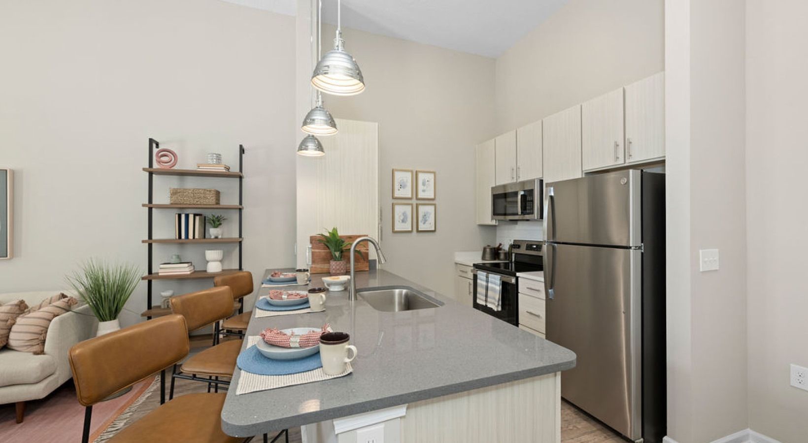 Kitchen with island seating, stainless steel appliances, and overhead lighting.