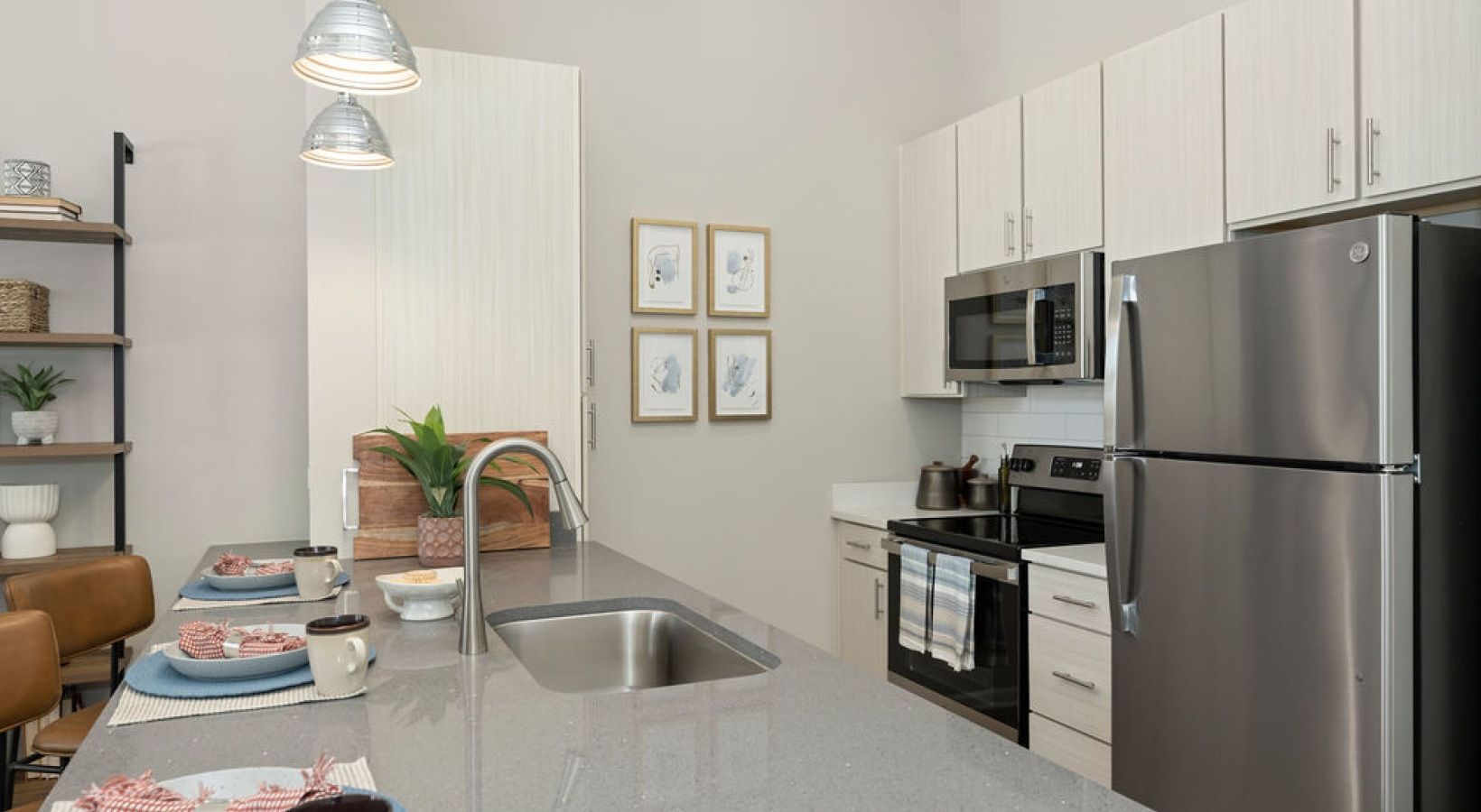 Modern kitchen with gray countertop, stainless steel appliances, and white cabinets. We invite you to visit 1001 Tyvola and take a tour of our 2-bedroom apartments in Charlotte, NC.