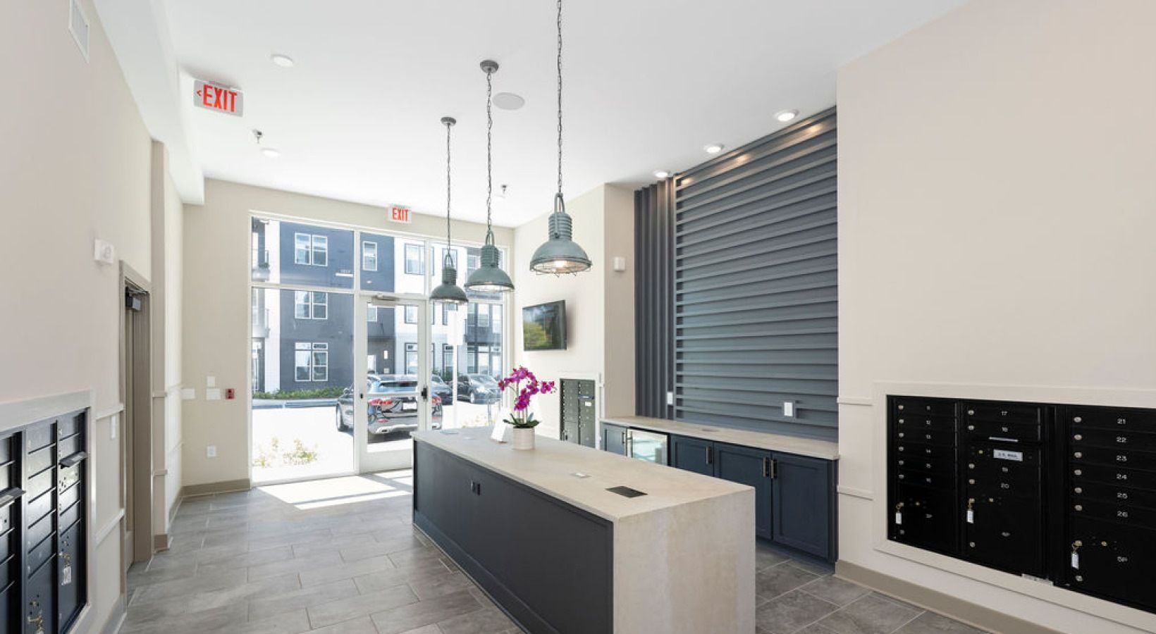 Apartment lobby with mailboxes, long counter, pendant lights, and large glass entrance. We invite you to visit 1001 Tyvola and take a tour of our pet-friendly, 1-bedroom apartments in Charlotte, NC.