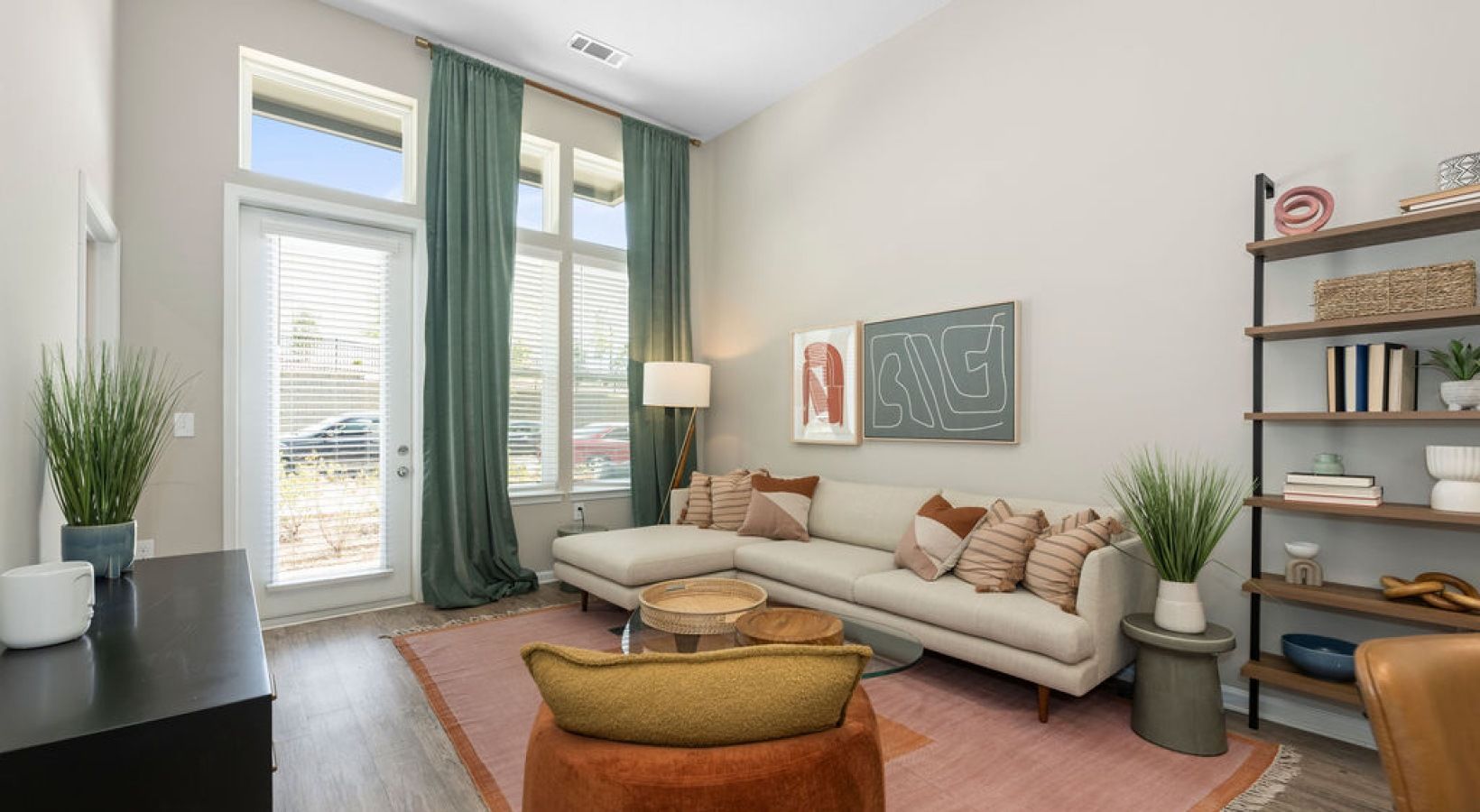 Living room with a large window, sectional sofa, and decorative items. We invite you to visit 1001 Tyvola and take a tour of our apartments near Central Piedmont Community College Harper Campus.