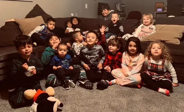 Group of children smiling and posing on a couch and carpet.