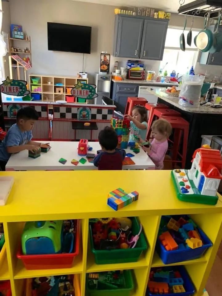 Children playing with blocks at a table in a brightly colored playroom.