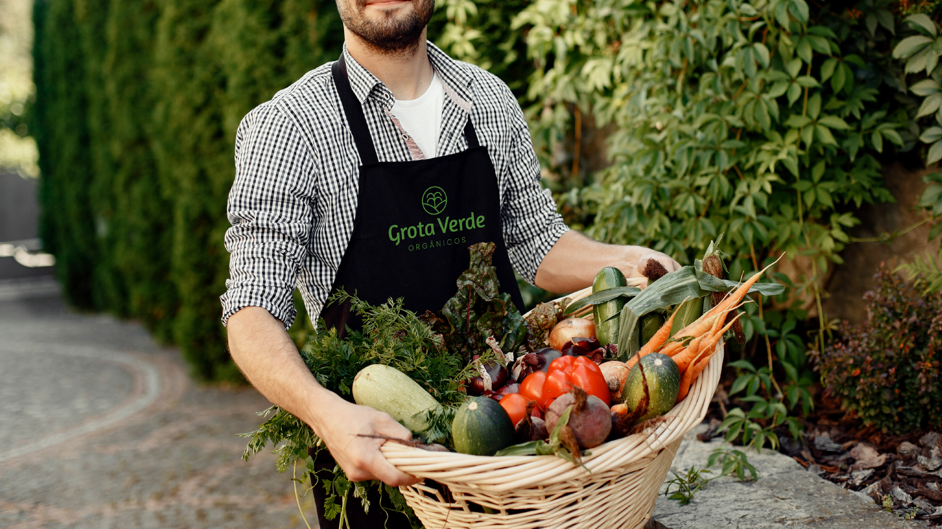 Um homem de avental está segurando uma cesta de vegetais.